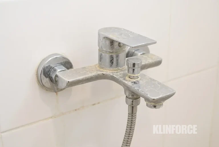Kerak putih kekuningan di keran dan keramik kamar mandi